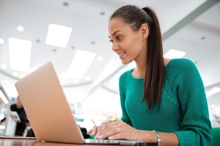 Portrait of a happy female student using laptop computer in university